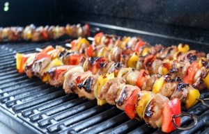 Meat and veggie kebabs roasting on a grill.